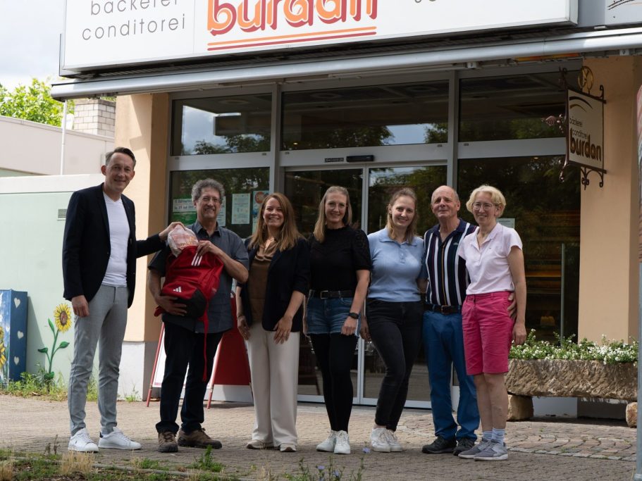 Gruppe von sieben Menschen vor einem Geschäft mit der Aufschrift „Burdan“.