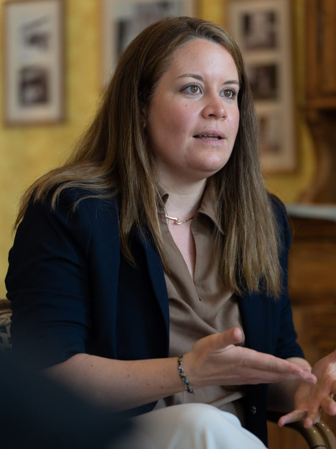 Frau mit langen Haaren in einem blauen Blazer, die spricht.