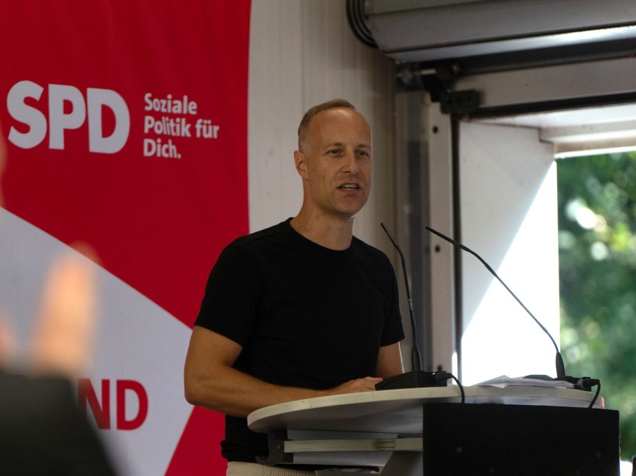 Mann spricht am Rednerpult vor einem SPD-Poster.